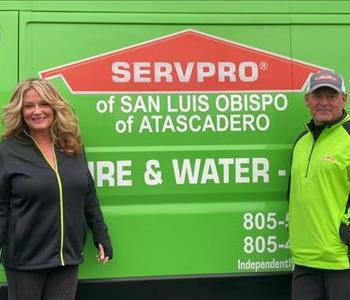 Female and a Male wearing a green and black jacket in front of a green van